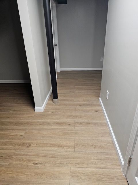 A hallway with a wooden floor and gray walls.