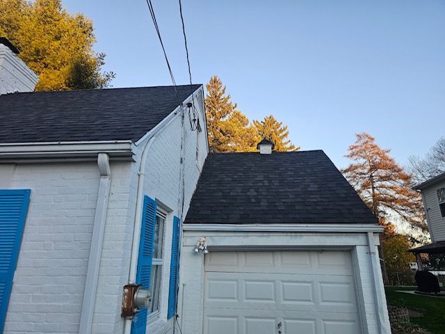 A white house with a black roof and blue shutters
