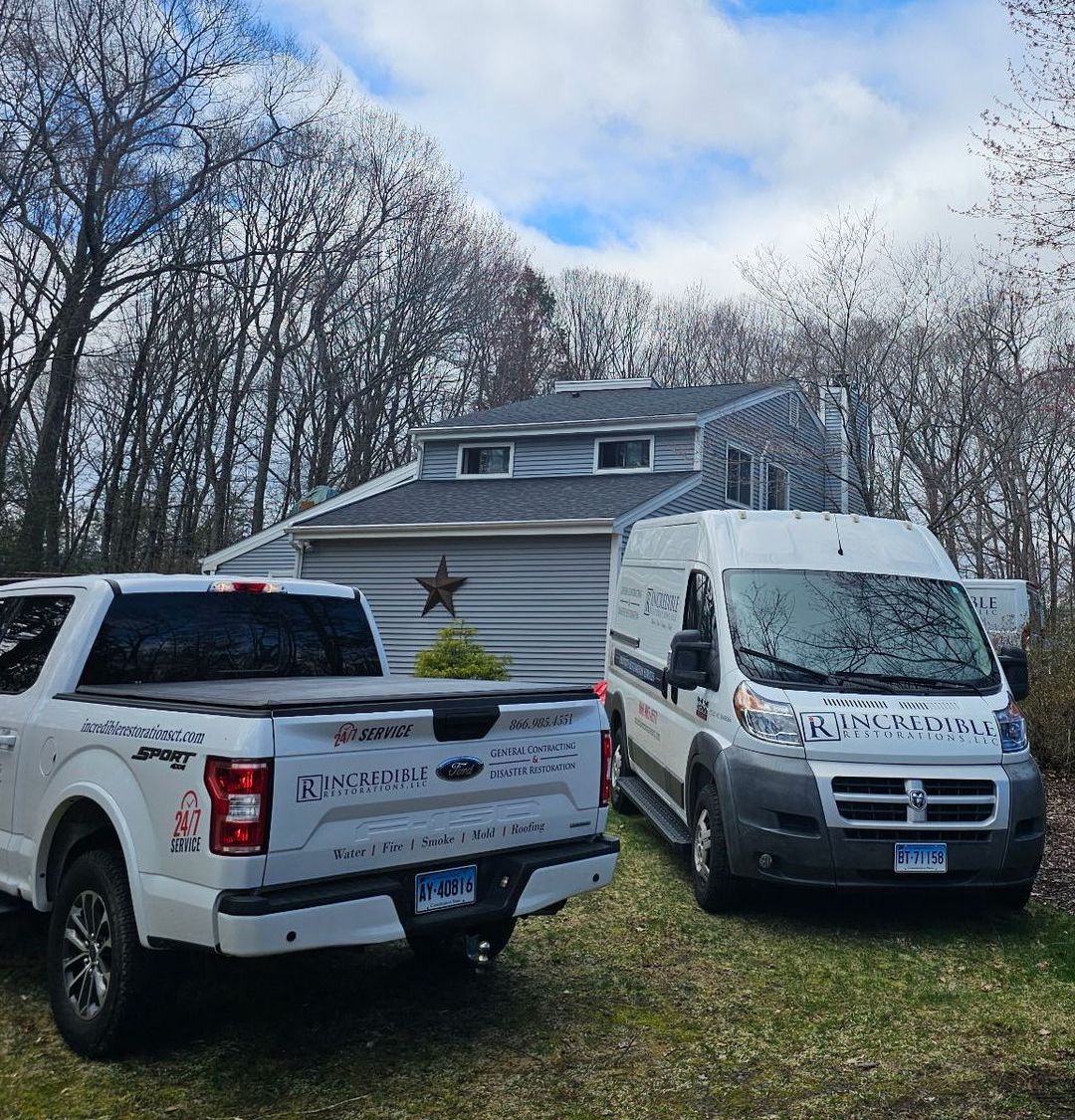 Two trucks and a van are parked in front of a house.