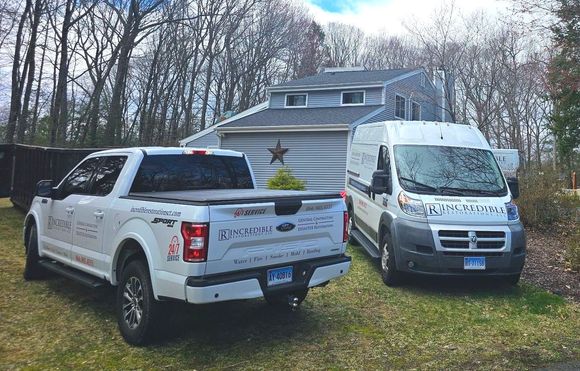 Two trucks and a van are parked in front of a house.