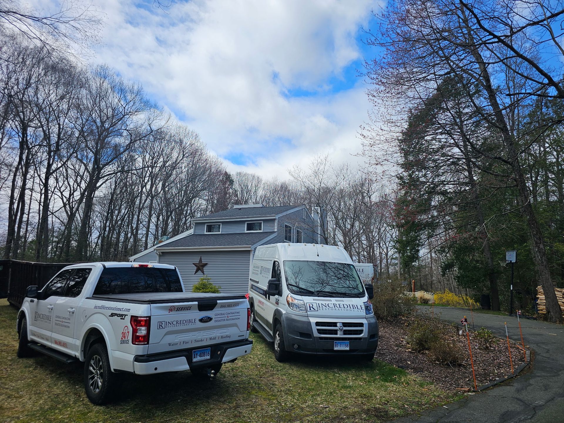 Two trucks and a van are parked in front of a house.