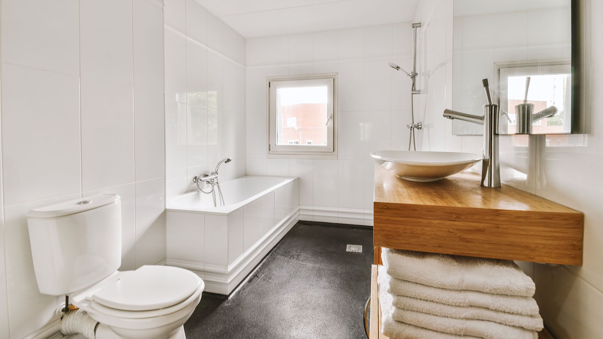 A bathroom with a toilet , sink , bathtub and mirror.