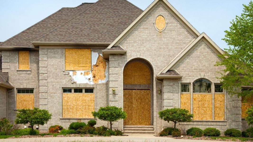 A large brick house with boarded up windows and doors.