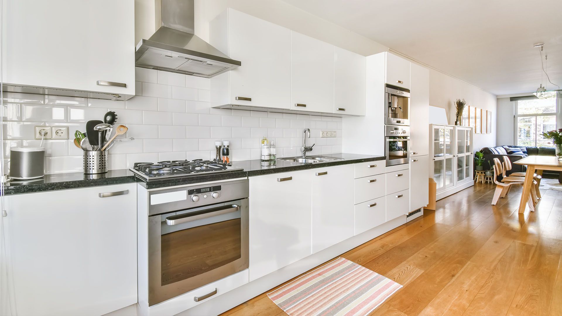 A kitchen with white cabinets , stainless steel appliances , and hardwood floors.