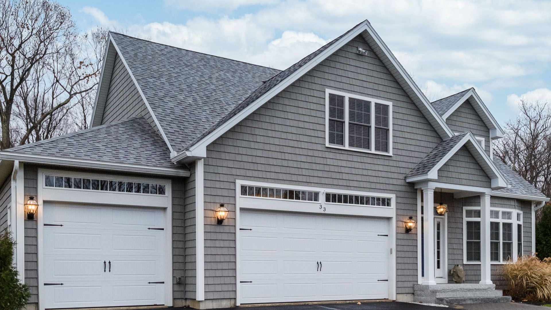 A large gray house with white garage doors and a gray roof