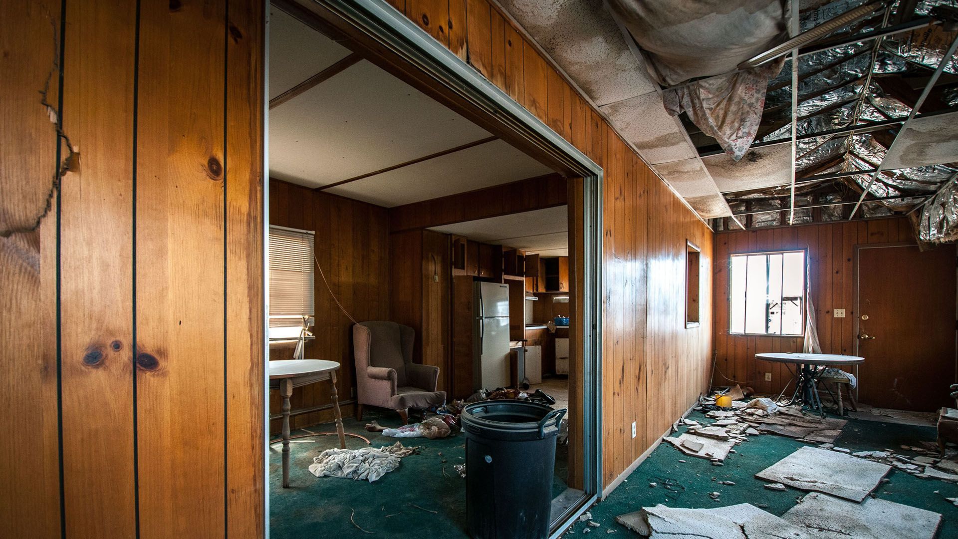 A room with wood paneling and a trash can in it.