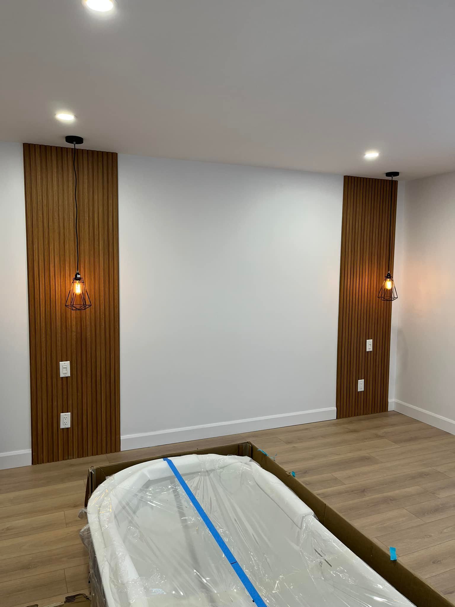 Dans une pièce au parquet clair, des murs d'accent en bois, agrémentés d'appliques murales, encadrent un mur blanc.