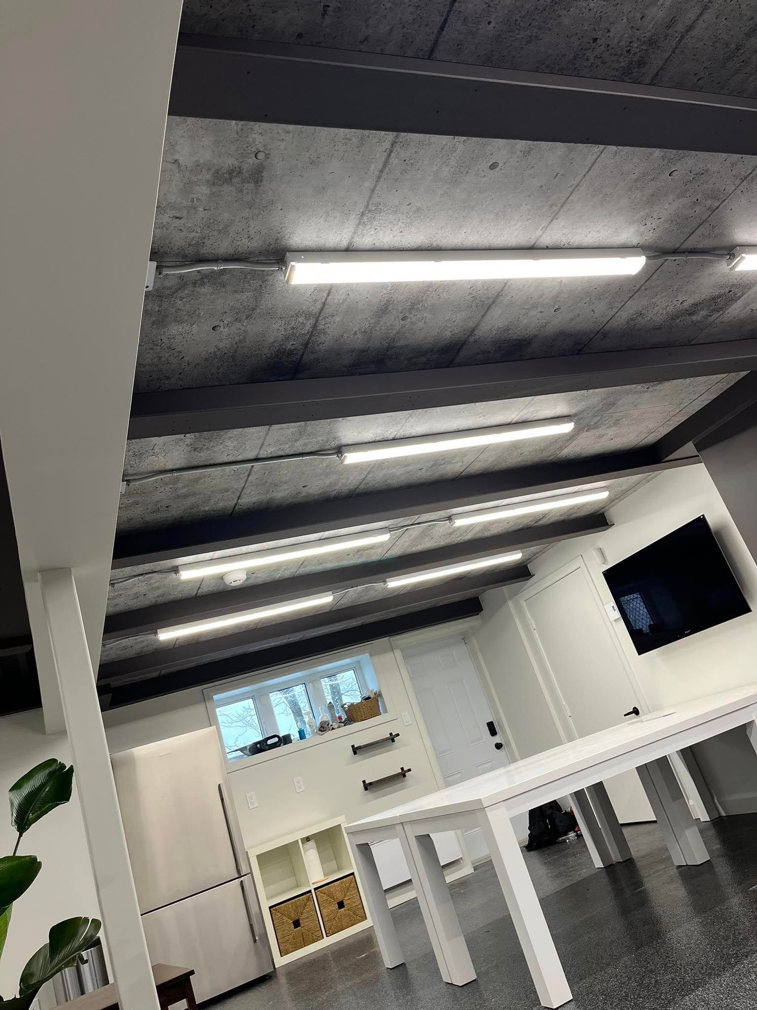 Intérieur de bureau avec bureaux blancs, plafond gris et éclairage vif au plafond.