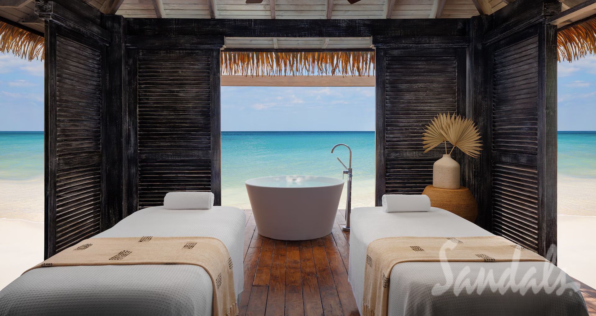 Spa room overlooking the ocean, with massage tables and a bathtub.