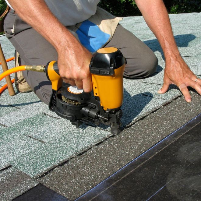 man installing shingles on a roof