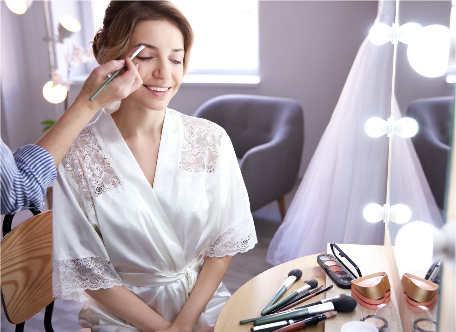 A woman is getting her makeup done in front of a mirror.