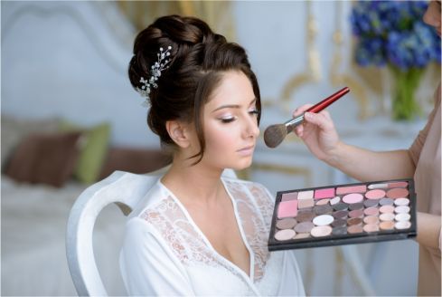 A woman is getting her makeup done by a makeup artist.