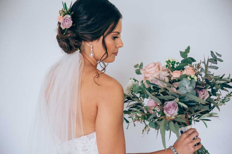 The bride is wearing a veil and holding a bouquet of flowers.