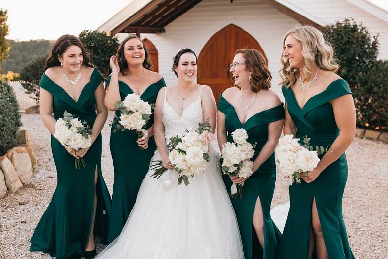 A bride and her bridesmaids are posing for a picture in front of a church.