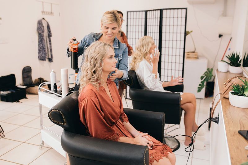 A woman is getting her hair done by a hairdresser in a salon.