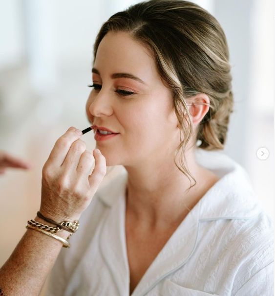 A woman is applying makeup to her lips with a brush