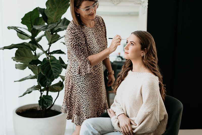 A woman is applying makeup to another woman 's face.