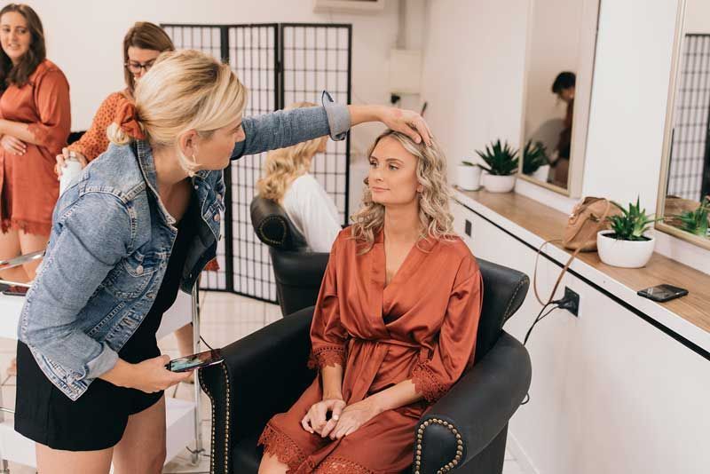 A woman is getting her hair done by a hairdresser in a salon.