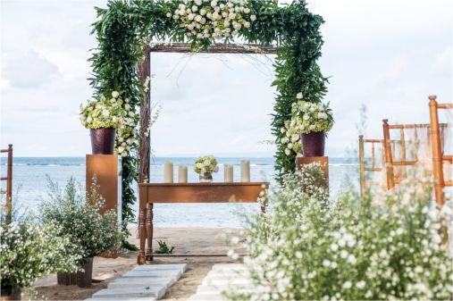 A bride and groom are kissing on a wooden dance floor in a large room.