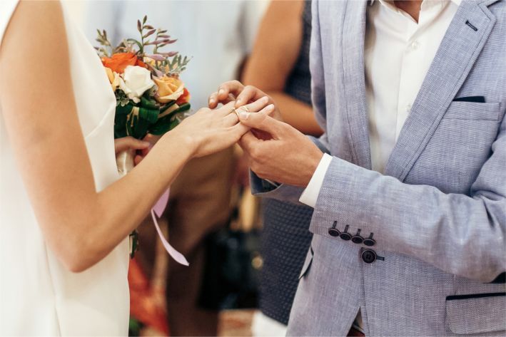 A bride and groom are standing on a beach holding hands.