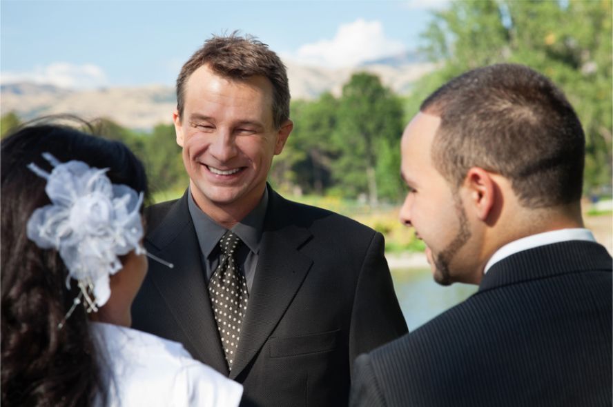 A bride and groom are posing for a picture on the beach.