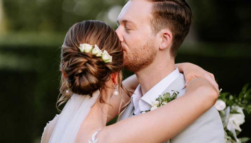 A bride and groom are kissing on their wedding day.