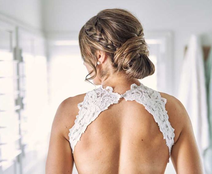 The back of a woman in a wedding dress with a braided bun.