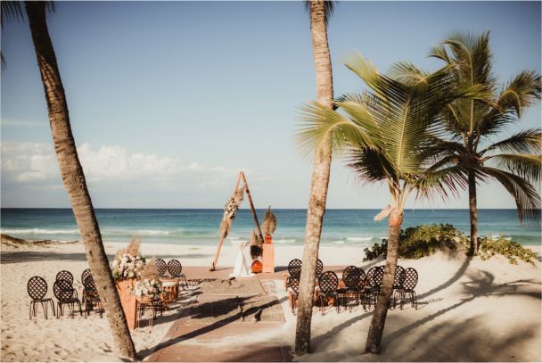 A bride and groom are posing for a picture on the beach.