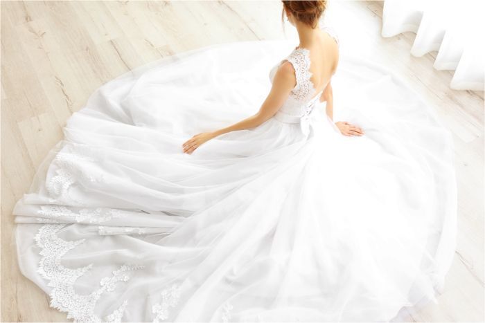 A bride and groom are standing on a beach holding hands.