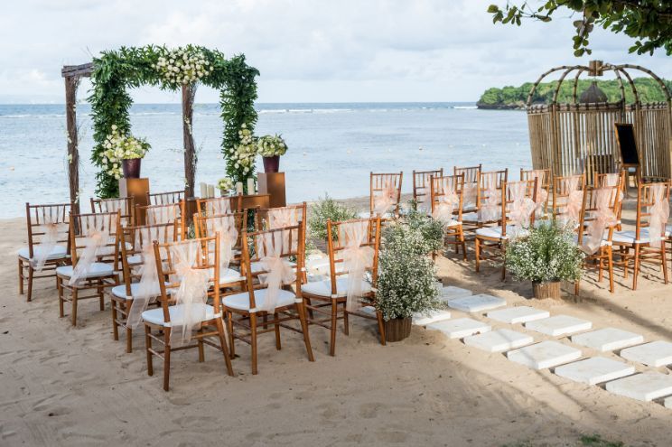 A bride and groom are kissing on a wooden dance floor in a large room.