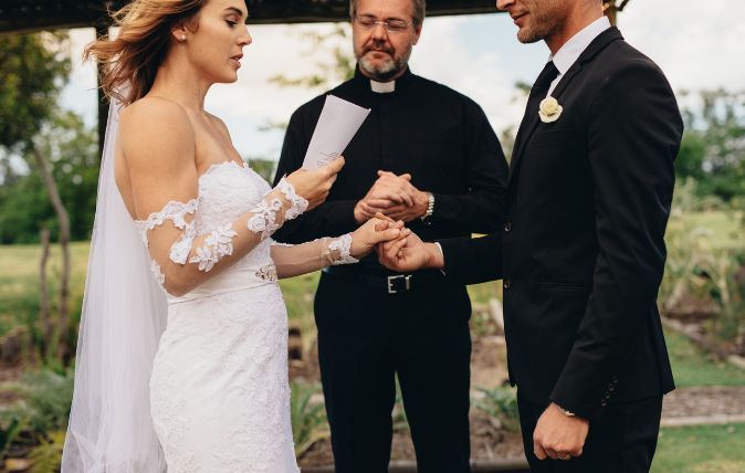 A bride and groom are standing on a beach holding hands.