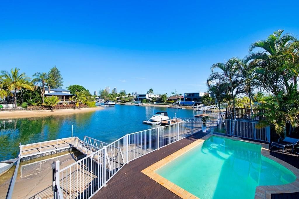 A large swimming pool surrounded by a fence overlooking a body of water.