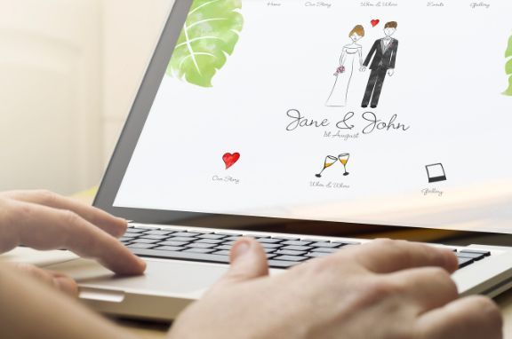 A person is typing on a laptop with a picture of a bride and groom on the screen.