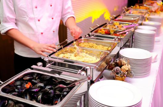 A chef is preparing food at a buffet table.