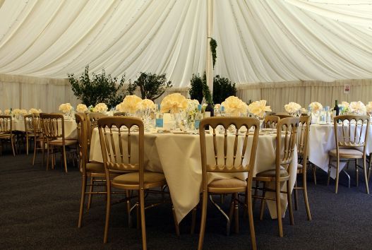 A tent with tables and chairs set up for a wedding reception