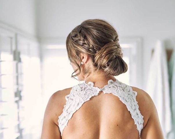 The back of a woman in a wedding dress with a braided bun.