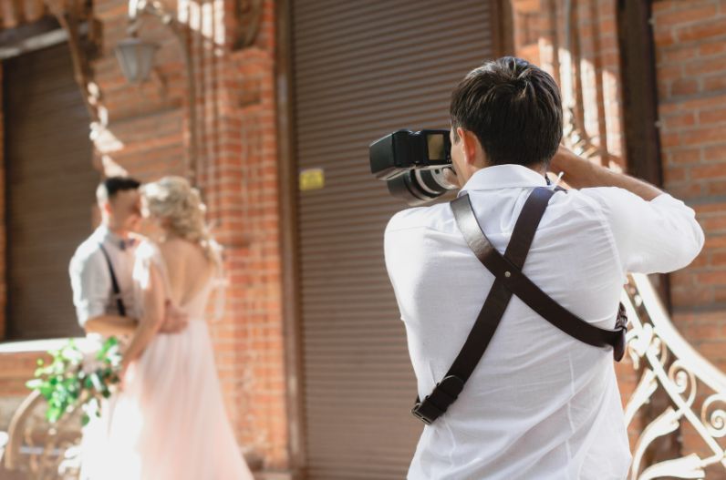 A man is taking a picture of a bride and groom.