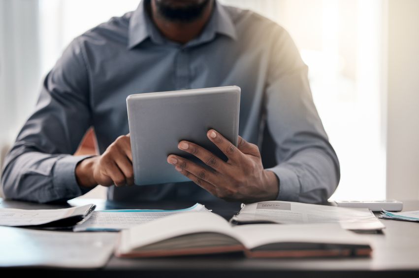 A man is sitting at a desk using a tablet computer.