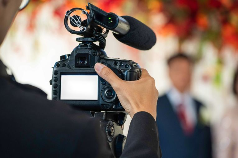 A man is holding a camera with a microphone attached to it.