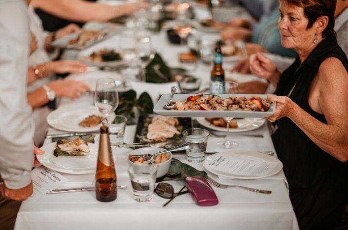 A woman is holding a tray of food at a long table.