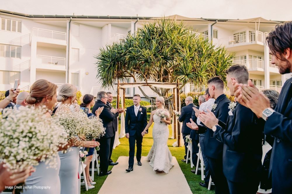 A bride and groom are walking down the aisle at their wedding.