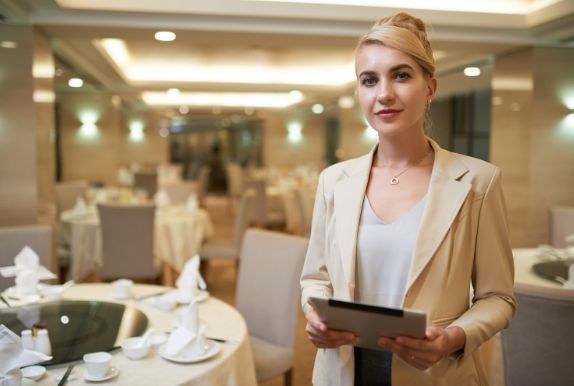 A woman is holding a tablet in a restaurant.