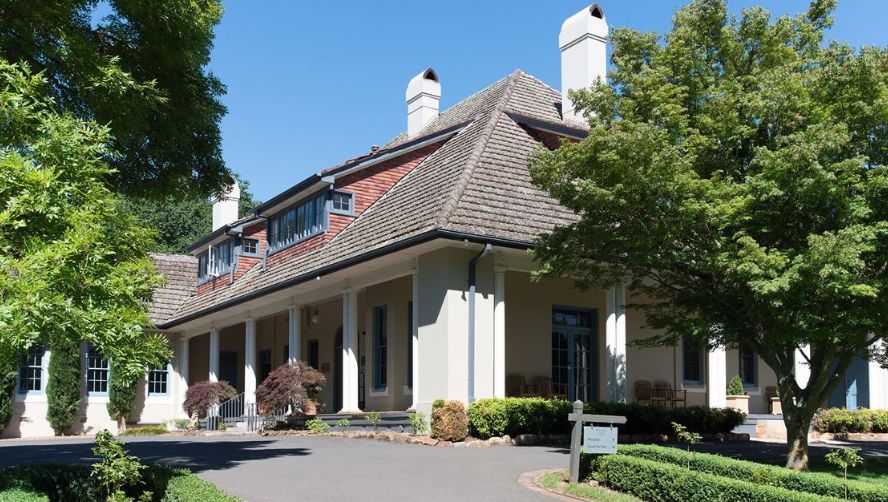 A large white house with a porch and trees in front of it