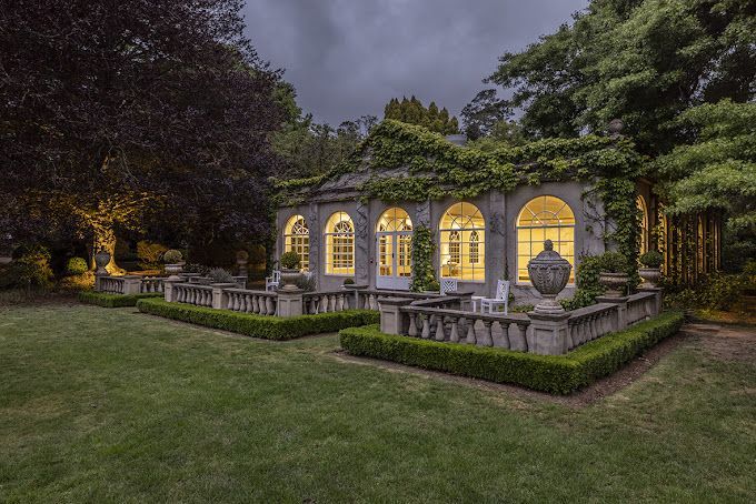 A large house with arched windows is lit up at night.