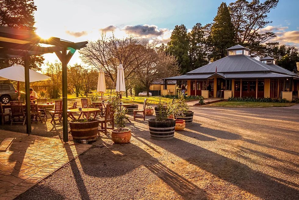 A patio area with tables and chairs in front of a building at sunset.