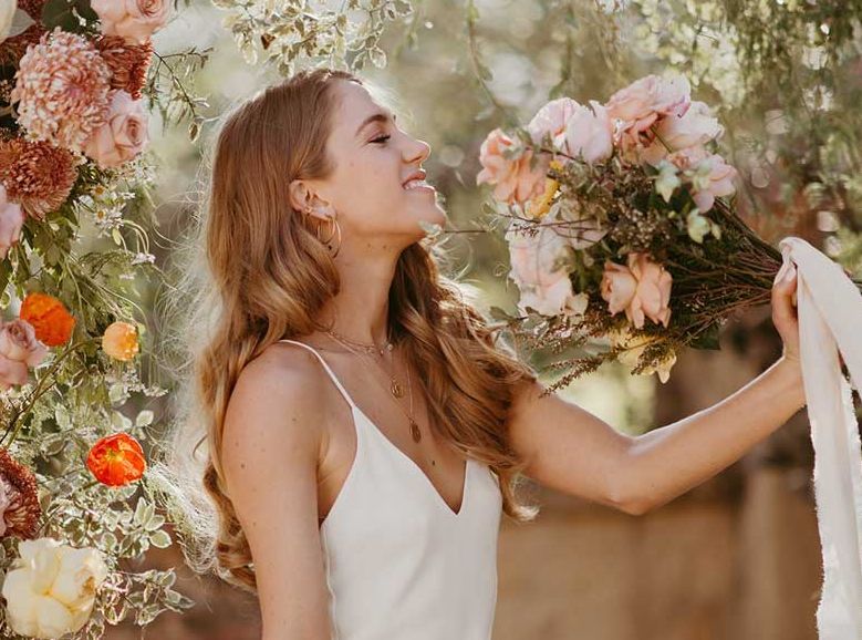 A woman in a white dress is holding a bouquet of flowers.