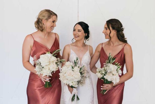 A bride and her bridesmaids are standing next to each other holding bouquets of white flowers.