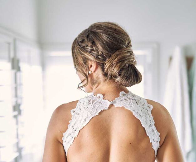 The back of a woman in a wedding dress with a braided bun.