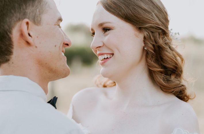 A bride and groom are looking at each other and smiling.