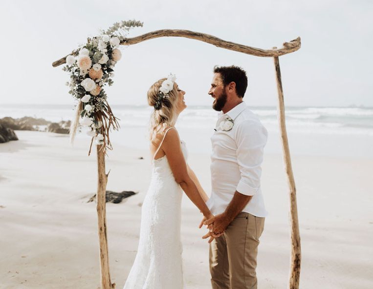 A bride and groom are kissing on a wooden dance floor in a large room.